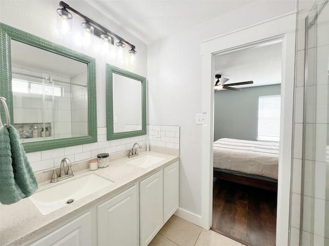 ensuite bathroom featuring tile patterned flooring, connected bathroom, tasteful backsplash, and a sink