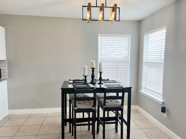 dining area with light tile patterned floors, an inviting chandelier, and baseboards