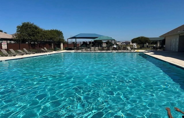 community pool with a patio and fence