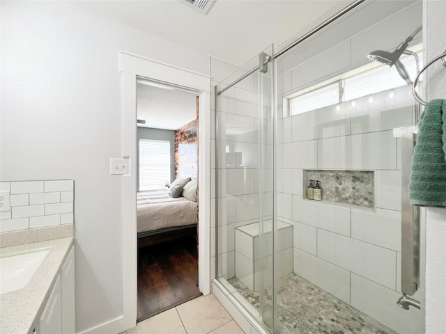 ensuite bathroom with tile patterned flooring, a shower stall, and a wealth of natural light