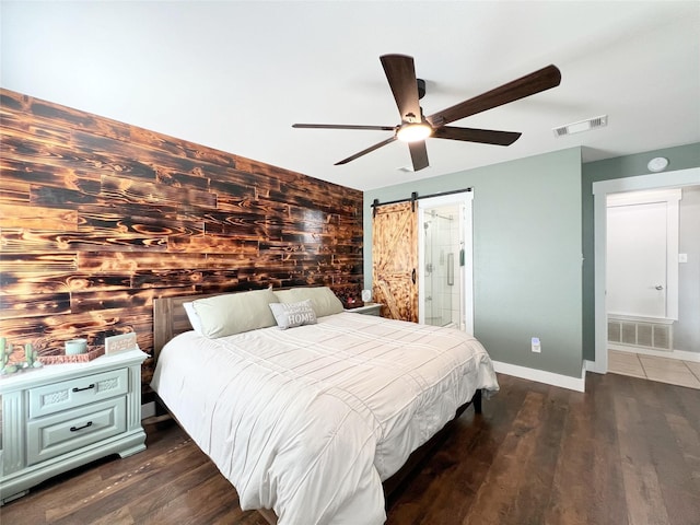 bedroom with visible vents, a barn door, baseboards, and dark wood-style floors