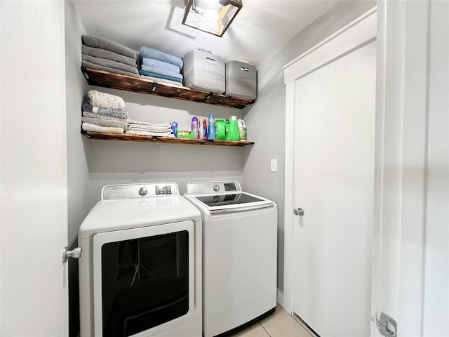 washroom featuring light tile patterned flooring, laundry area, and washing machine and dryer