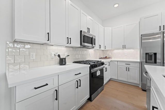 8305 Springwood Creek Ln, Houston, TX 77055 - kitchen featuring stainless steel appliances, light countertops, white cabinets, tasteful backsplash, and light wood-style floors