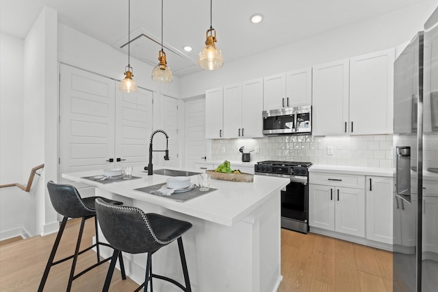 8305 Springwood Creek Ln, Houston, TX 77055 - kitchen with appliances with stainless steel finishes, a center island with sink, decorative backsplash, a kitchen breakfast bar, and light wood-style flooring