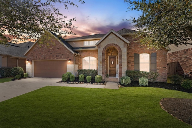 view of front facade featuring brick siding, an attached garage, concrete driveway, and a front yard