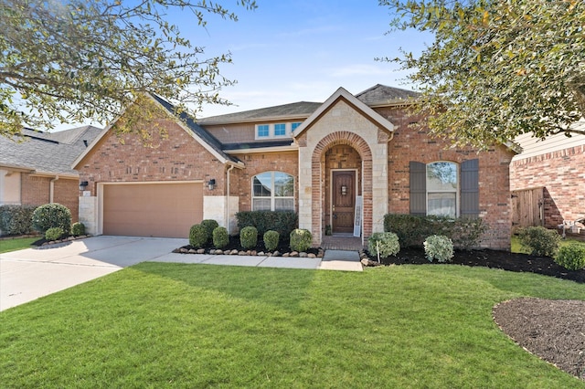 view of front of home featuring a front yard, roof with shingles, an attached garage, concrete driveway, and brick siding