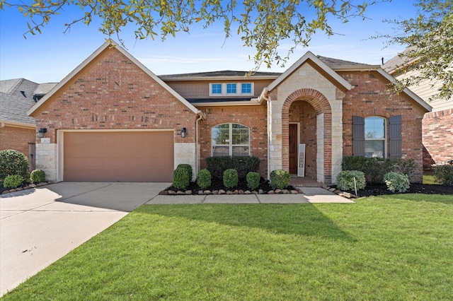 view of front facade featuring brick siding, a garage, driveway, and a front lawn