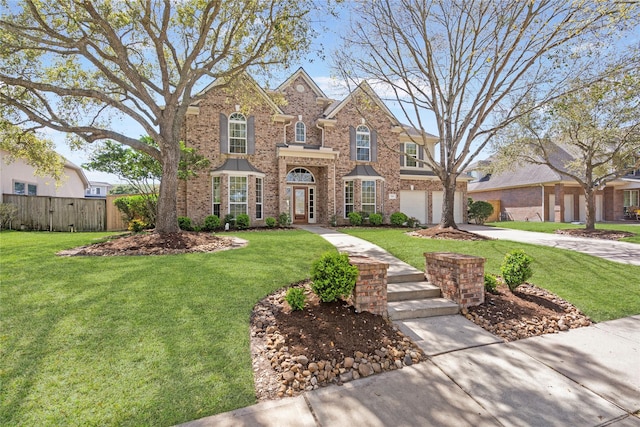 traditional-style house with brick siding, a front lawn, driveway, and fence