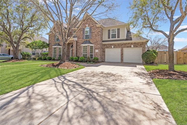 traditional-style house featuring fence, concrete driveway, an attached garage, a front yard, and brick siding