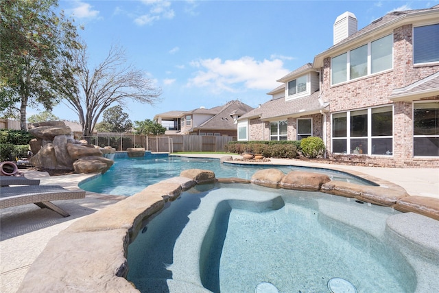 view of swimming pool with a pool with connected hot tub and fence