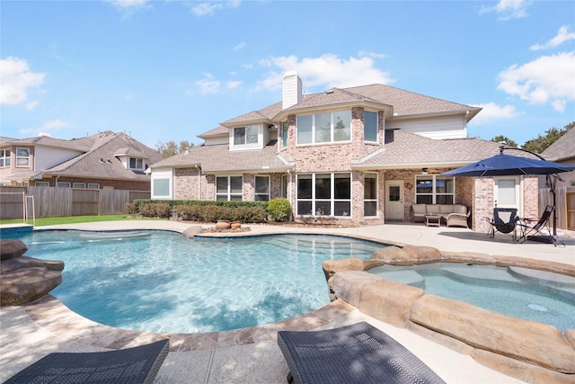 view of pool with a patio area, fence, and a pool with connected hot tub