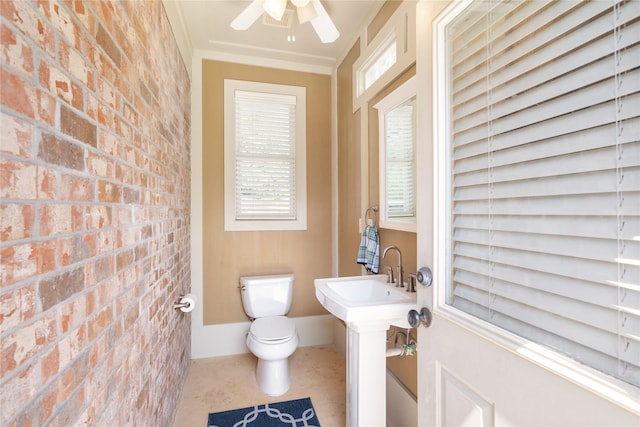 bathroom featuring toilet, brick wall, and a ceiling fan