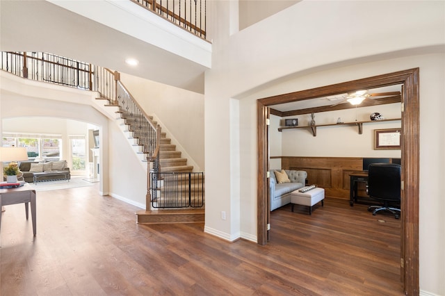 foyer with ceiling fan, baseboards, stairs, wood finished floors, and arched walkways