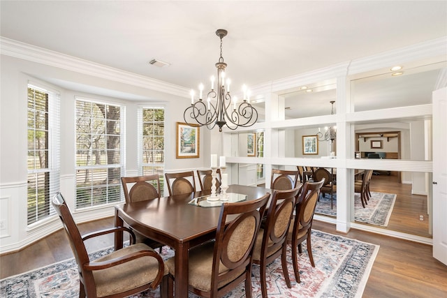 dining room with visible vents, a wainscoted wall, ornamental molding, an inviting chandelier, and wood finished floors