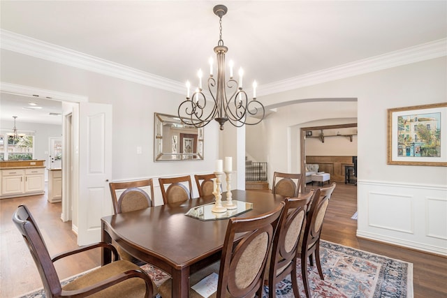 dining room with an inviting chandelier, wood finished floors, a wainscoted wall, and ornamental molding