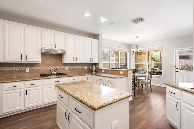 kitchen with an inviting chandelier, tasteful backsplash, dark wood-style flooring, and under cabinet range hood