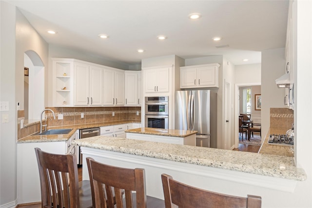 kitchen featuring decorative backsplash, white cabinetry, appliances with stainless steel finishes, and a sink