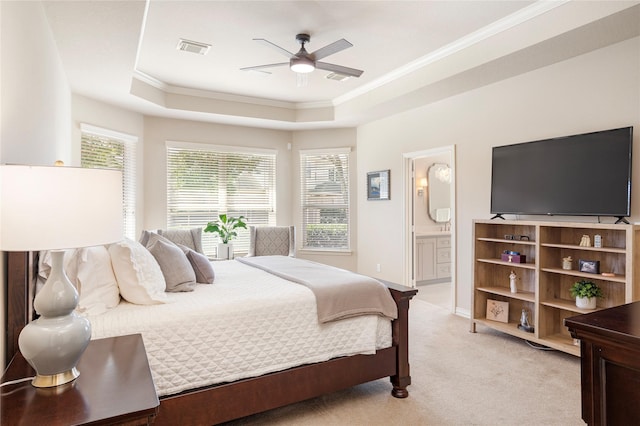 bedroom featuring visible vents, a tray ceiling, ornamental molding, light colored carpet, and connected bathroom