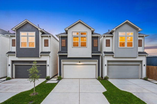 multi unit property featuring concrete driveway, an attached garage, and a shingled roof