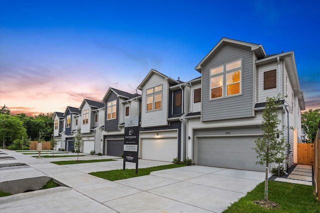 townhome / multi-family property with a residential view, concrete driveway, and an attached garage