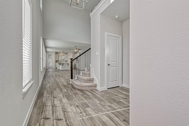 entryway featuring baseboards, wood finished floors, stairs, and a textured wall