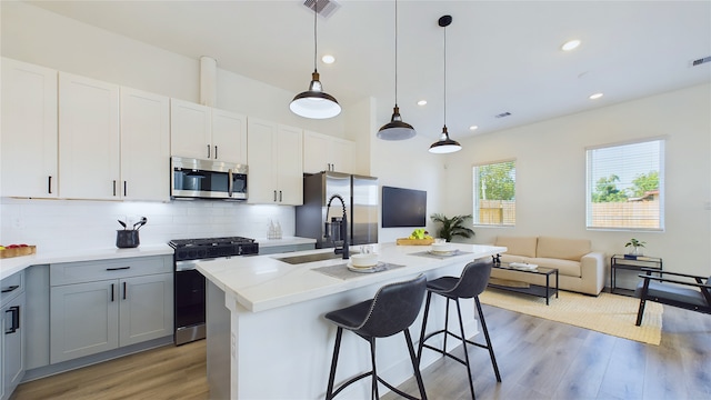 kitchen featuring visible vents, light wood finished floors, stainless steel appliances, light countertops, and decorative backsplash