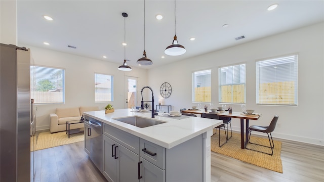 kitchen with visible vents, light wood-type flooring, gray cabinets, stainless steel appliances, and a sink