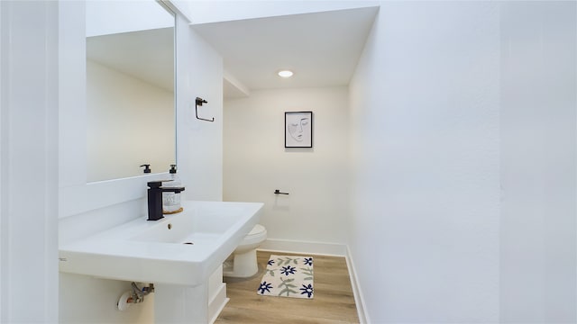 half bathroom featuring toilet, baseboards, and wood finished floors