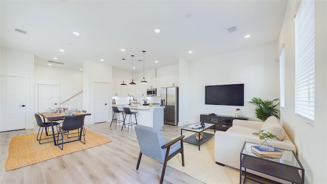 living room with recessed lighting, visible vents, and light wood-style floors