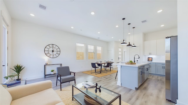 kitchen with visible vents, a sink, freestanding refrigerator, light wood finished floors, and light countertops