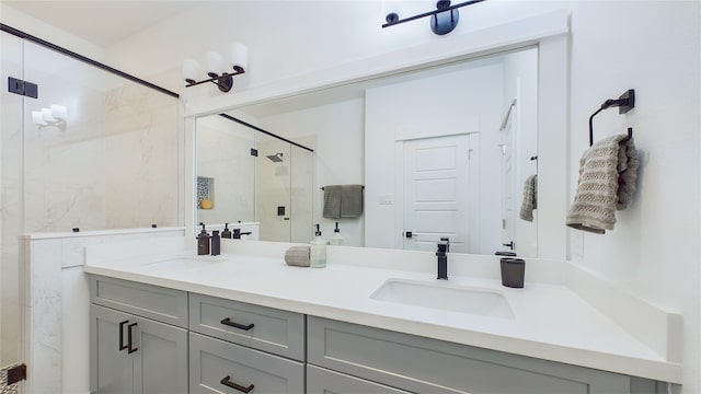 full bathroom with a marble finish shower, double vanity, and a sink