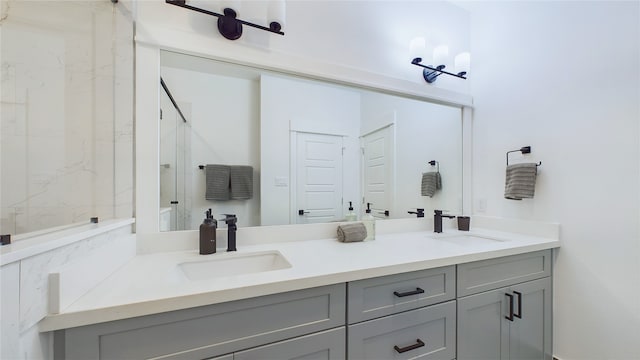 full bath featuring a sink, a marble finish shower, and double vanity