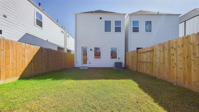 rear view of property with cooling unit, a lawn, and a fenced backyard