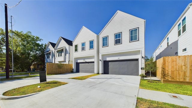 view of front of home with driveway, an attached garage, board and batten siding, and fence