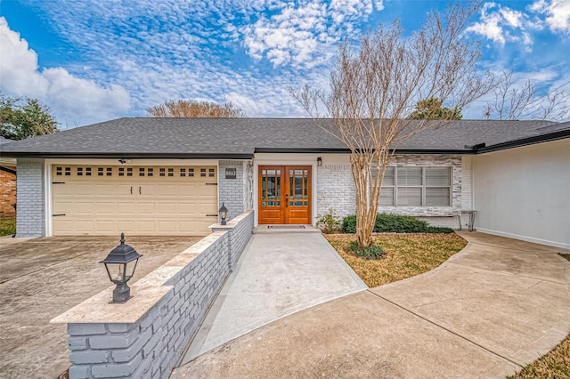 single story home featuring brick siding, french doors, concrete driveway, and an attached garage