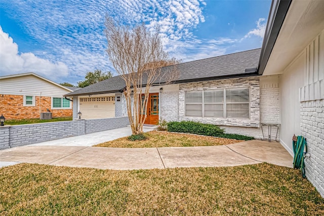 ranch-style house featuring brick siding, a shingled roof, a front lawn, central AC, and driveway