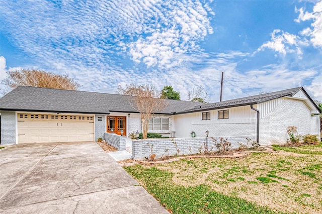 ranch-style house featuring brick siding, an attached garage, driveway, and roof with shingles