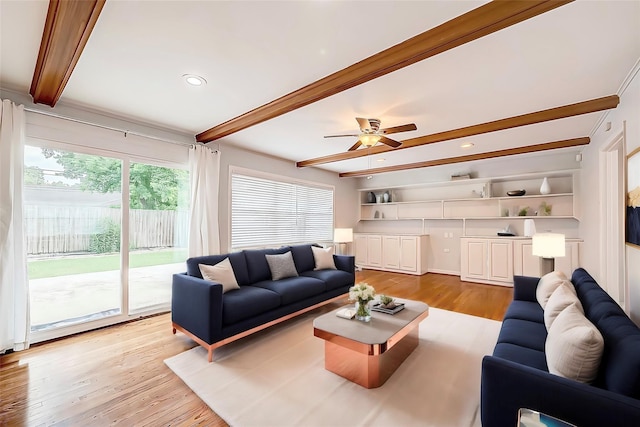 living area with beam ceiling, ceiling fan, and light wood finished floors