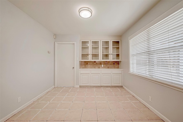 empty room with baseboards and light tile patterned flooring