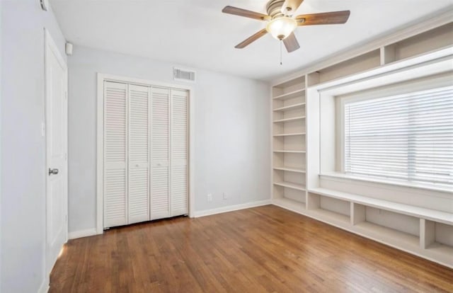 unfurnished bedroom with a ceiling fan, wood finished floors, visible vents, baseboards, and a closet