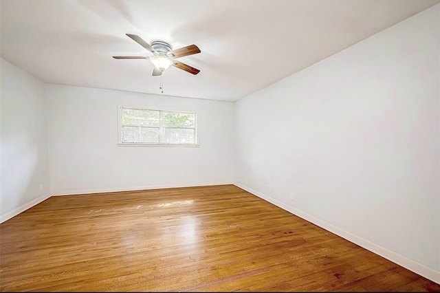 spare room featuring wood finished floors, baseboards, and ceiling fan