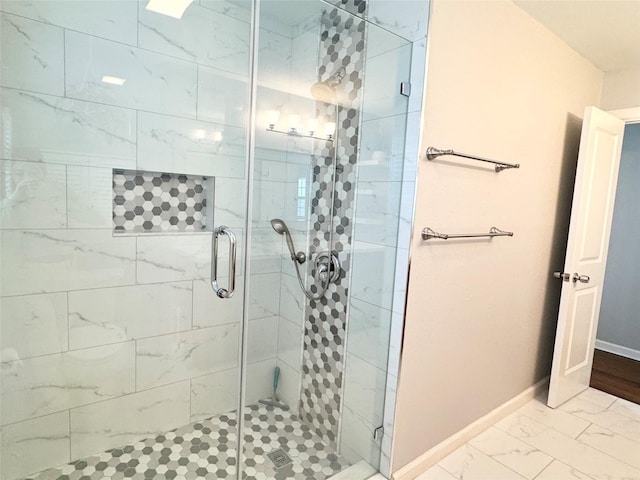 full bathroom featuring baseboards, marble finish floor, and a shower stall