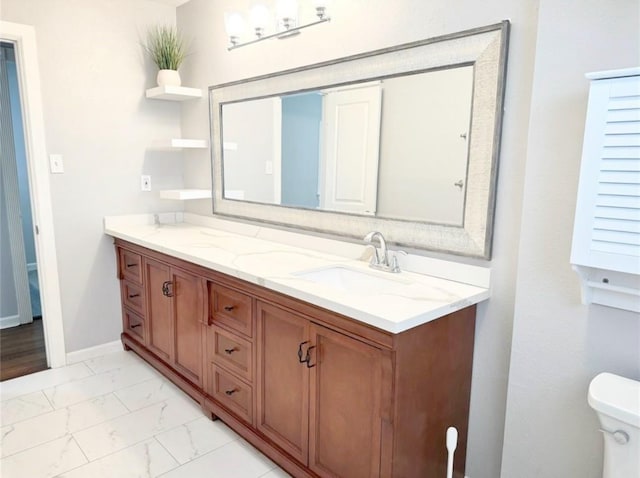 bathroom featuring vanity, toilet, baseboards, and marble finish floor