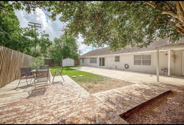 view of yard with a patio, fence, outdoor dining area, an outdoor structure, and a storage unit