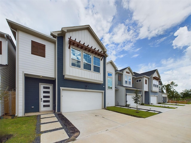 townhome / multi-family property with a garage, a residential view, board and batten siding, and concrete driveway