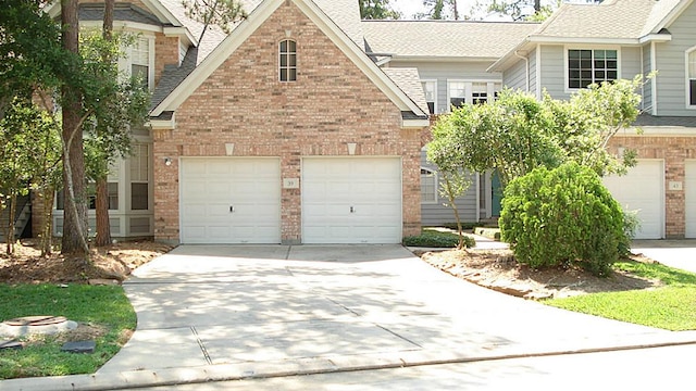 view of front facade with brick siding, driveway, and roof with shingles