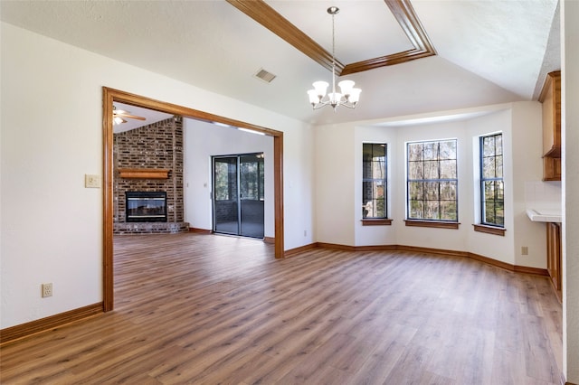 unfurnished living room featuring visible vents, wood finished floors, an inviting chandelier, a fireplace, and vaulted ceiling