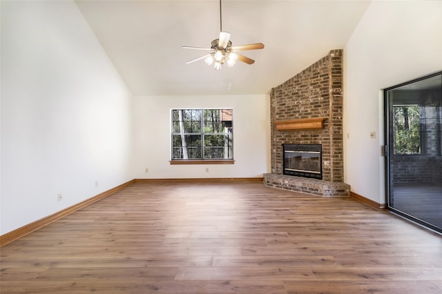 unfurnished living room featuring baseboards, ceiling fan, a fireplace, wood finished floors, and high vaulted ceiling