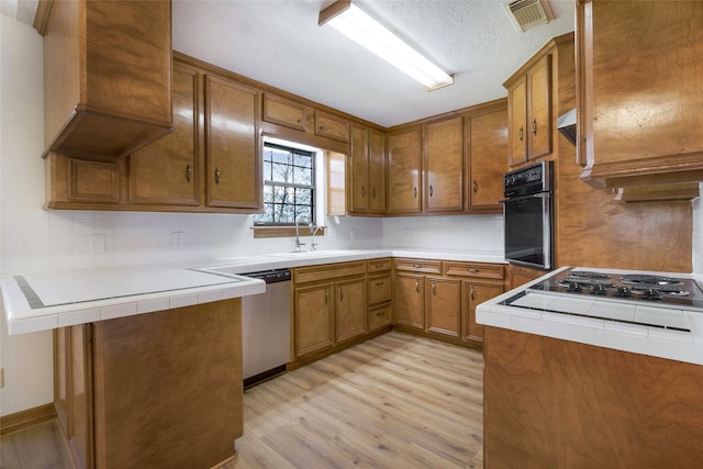 kitchen with wall oven, visible vents, and brown cabinetry