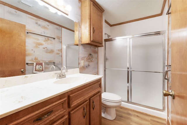 full bath with toilet, ornamental molding, a stall shower, wood finished floors, and vanity